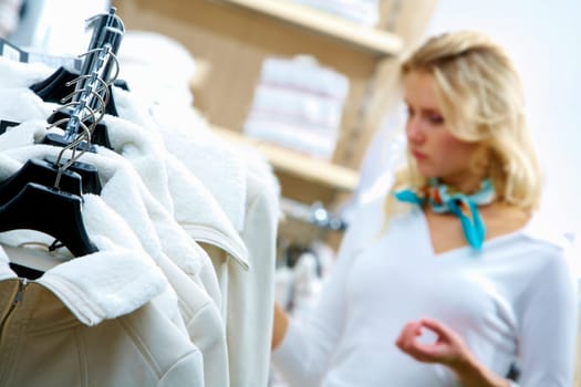 Close-up of woman choosing clothes with jackets in front