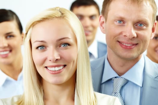Portrait of cheerful female looking at camera with several employees behind