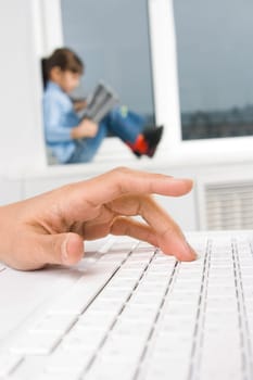Close-up of females hand over keyboard button with a child at background