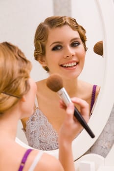 Image of pretty female looking in mirror and doing makeup