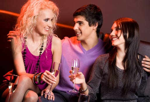 Photo of happy guy between two pretty girls chatting at xmas party