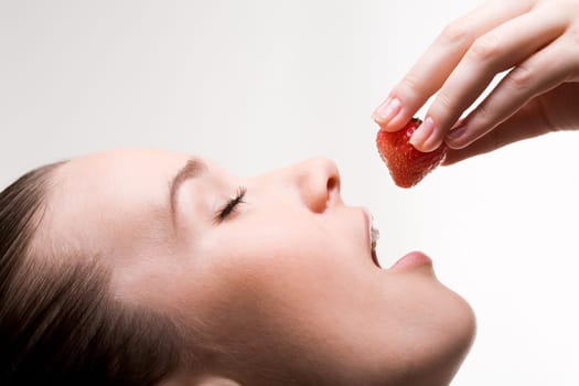 Image of pretty girl with open mouth and ripe strawberry in hand