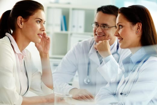 Portrait of confident practitioners consulting patient in hospital
