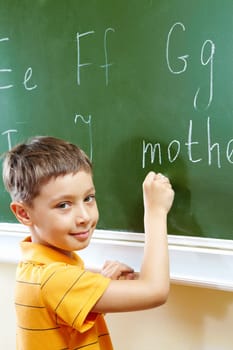 Portrait of smart schoolchild by the blackboard looking at camera