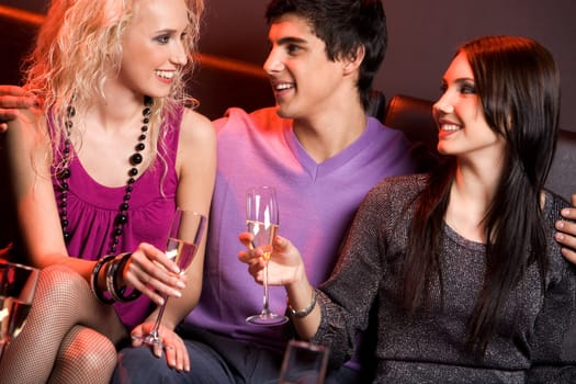 Portrait of smart young people holding champagne flutes and chatting with each other