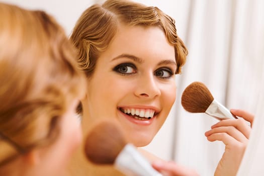 Image of pretty female looking in mirror and doing makeup