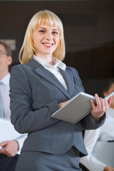 Portrait of confident business woman in suit holding the notepad on the background of people