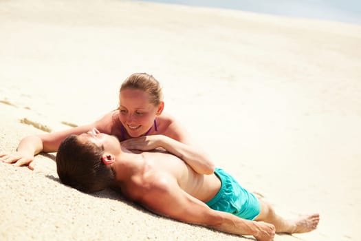 Photo of pretty woman looking at her husband while both lying on sand