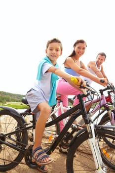 Portrait of family of three on bikes looking at camera and smiling