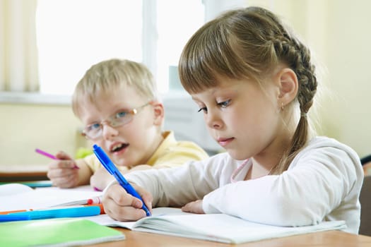 Portrait of smart schoolkids drawing at lesson in classroom