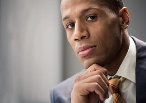 Portrait of confident entrepreneur keeping his hand on chin and looking at camera