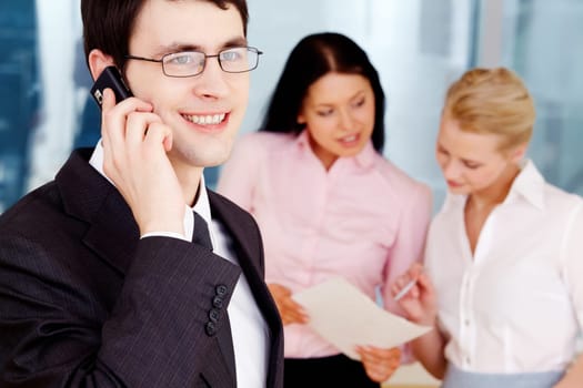 Image of handsome businessman speaking on the phone in working environment