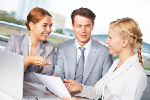 Image of successful businesspeople looking at each other while discussing plan at meeting in office