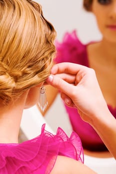 Image of pretty female putting on earrings