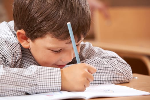 Photo of clever schoolkid writing something in his copybook at lesson