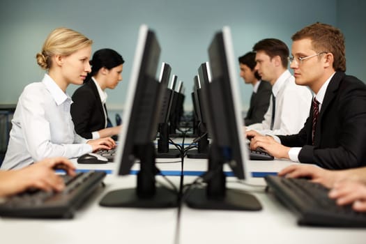 Image of smart people sitting at the tables at computer class
