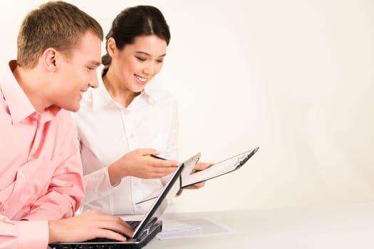 Photo of business partners sitting at workplace and looking at document with smiles