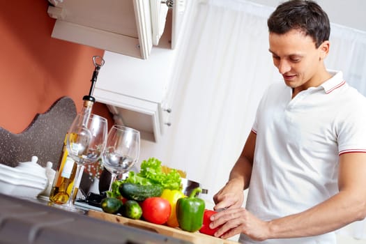 Portrait of young man cutting vegetables in the kitchen