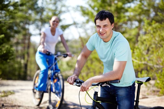 Portrait of a handsome man with his bike against his girlfriend
