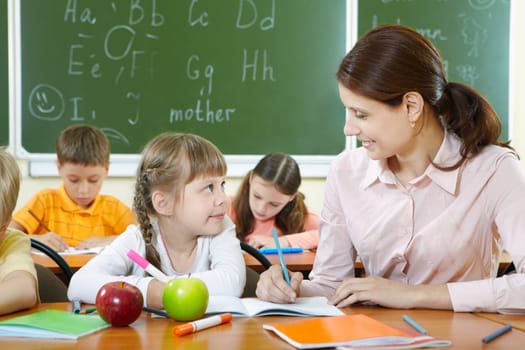 Portrait of smart girl and her teacher looking at each other at lesson in classroom