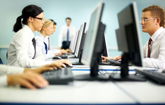 Businesspeople sitting at tables and looking at their monitors