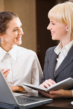 Two contemporary smiling businesswomen are chatting