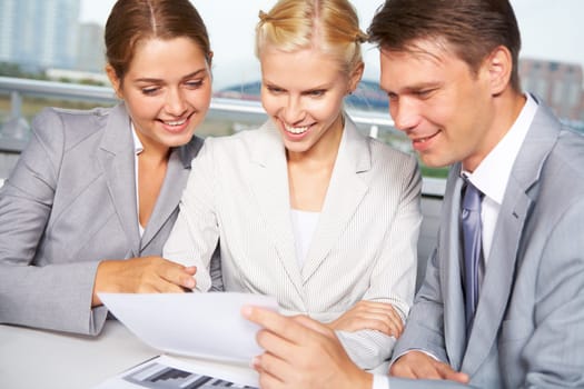 Image of successful businesspeople looking at document and discussing it