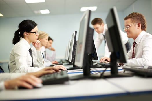 Businesspeople sit at tables and look at their monitors