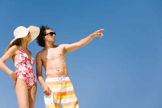 Photo of handsome guy pointing at something with attractive girlfriend near by