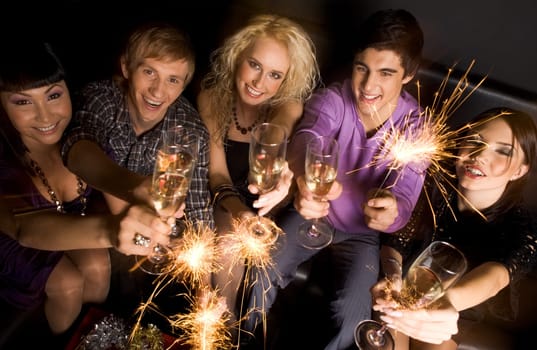 Above view of happy and friendly people raising their flutes full of champagne and looking at camera