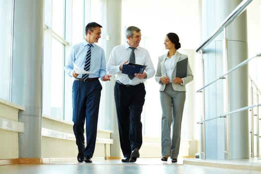 Confident business partners walking down in office building and discussing work