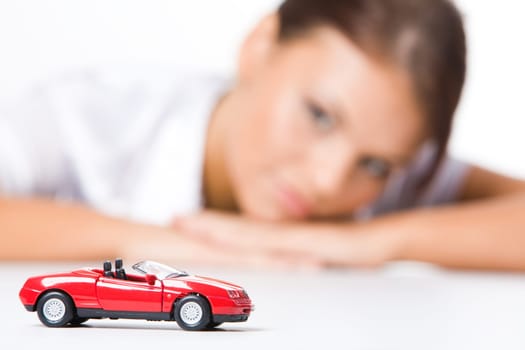 Red toy car on background of woman looking at it