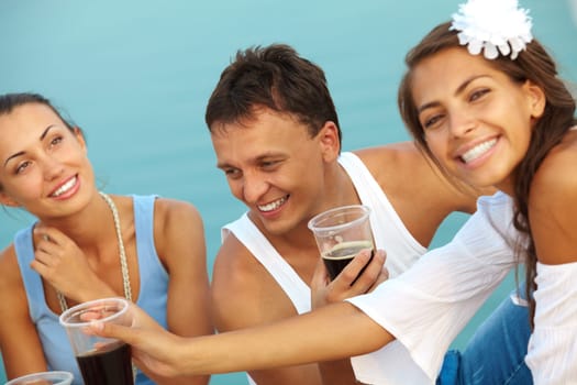 Image of happy guy with drink surrounded by girls at beach party