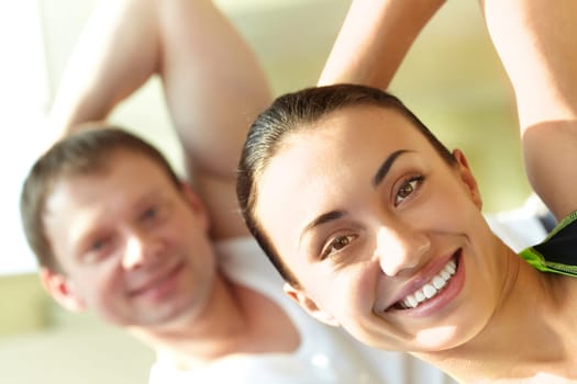 Portrait of young sporty couple doing exercise in gym