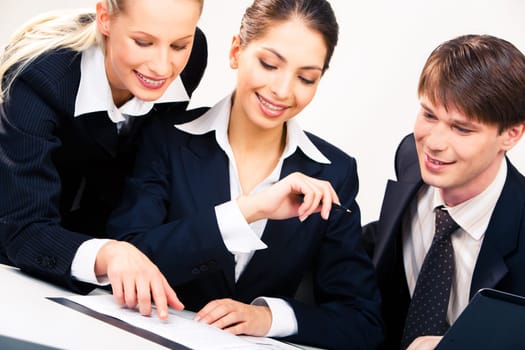 Portrait of three businesspeople looking at document placed on the table
