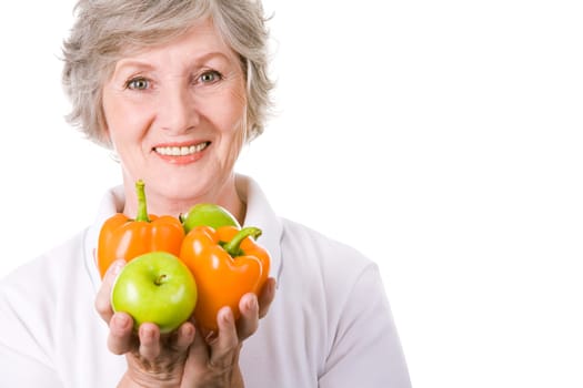 Portrait of aged female holding apples and peppers in hands