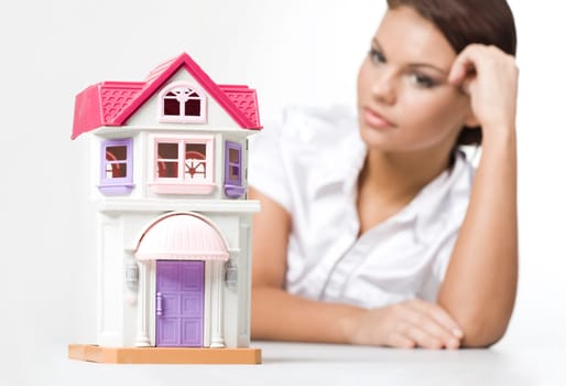 Miniature toy house with dreaming woman looking at it near by