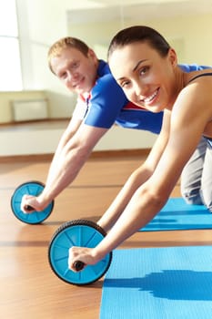 Portrait of young sporty couple doing exercise on floor