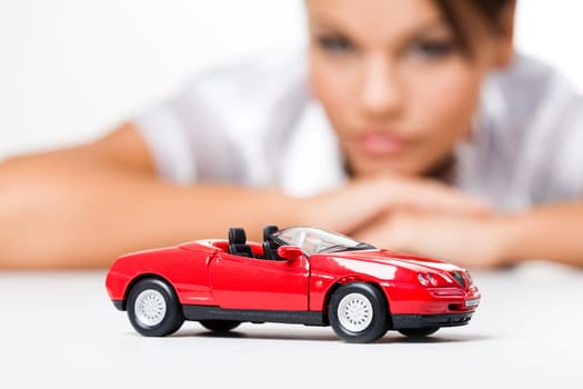 Close-up of a toy car with thinking woman at background