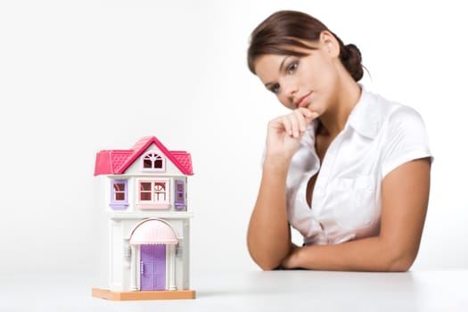Image of miniature toy house with pensive female at background
