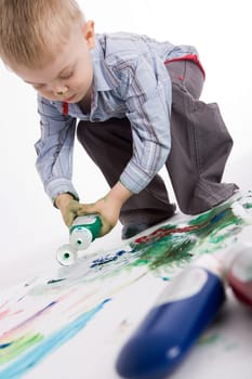 Photo of cute lad painting something with colorful gouache