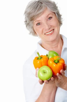 Portrait of aged female holding apples and peppers in hands