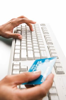 Close-up of female hand over keyboard pressing its button and holding plastic card