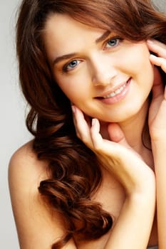 Portrait of charming girl touching her face and looking at camera