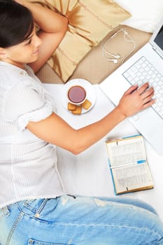 A young girl working on computer in bed