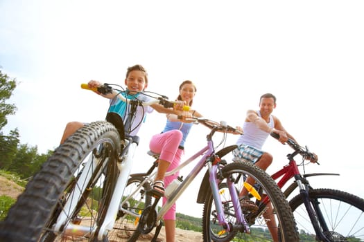 Family of three sitting on bikes, looking at camera and smiling