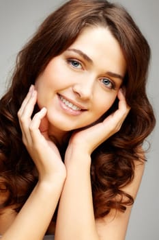 Portrait of feminine woman touching her face and looking at camera