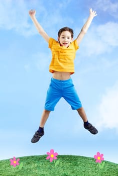 Image of happy boy jumping on the grass and looking at camera