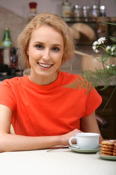 Portrait of smiling beautiful woman sitting at the table in the kitchen