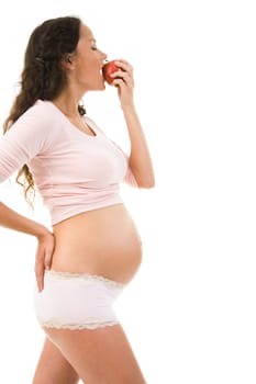 Photo of pregnant woman holding big red apple in hand while eating it with pleasure